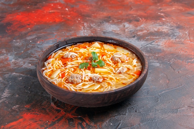 Vista laterale di una deliziosa zuppa di noodle con pollo in una ciotola marrone sullo sfondo scuro