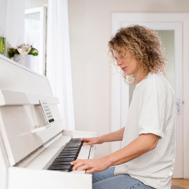 Vista laterale di una donna bionda che suona il pianoforte