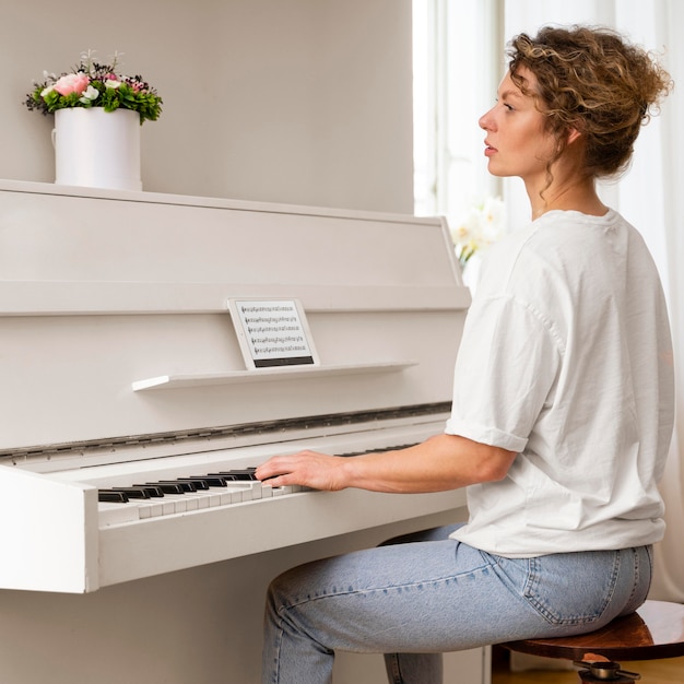 Vista laterale di una donna bionda che suona il pianoforte