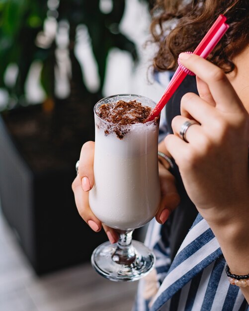 Vista laterale di una donna che beve il frappè al cioccolato