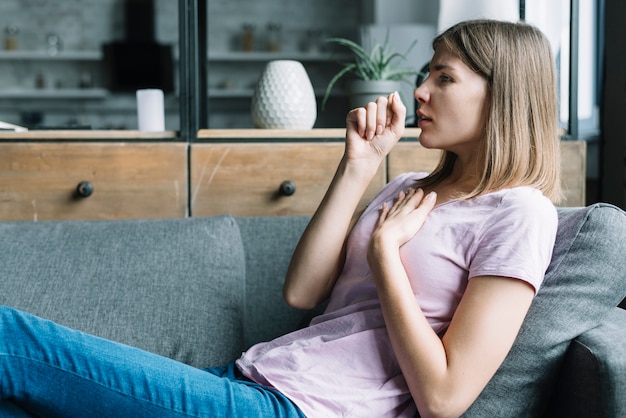 Vista laterale di una donna che si appoggia sul divano tosse