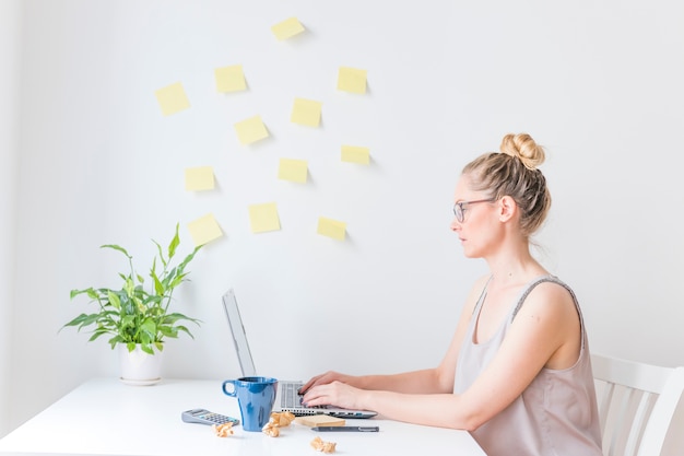 Vista laterale di una donna d&#39;affari che lavora al computer portatile in ufficio