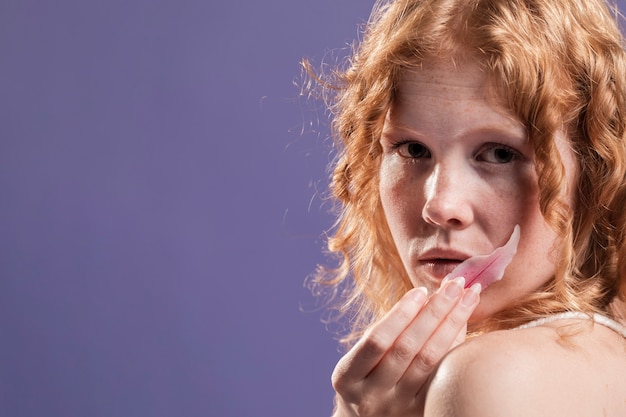 Vista laterale di una donna di redhead che propone con lo spazio della copia e del petalo
