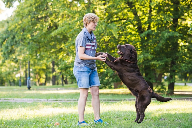 Vista laterale di una donna matura che gioca con il suo cane nel parco