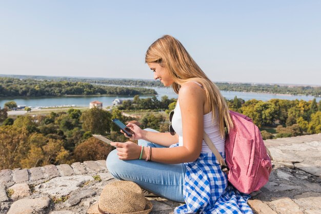 Vista laterale di una giovane donna alla ricerca di direzione nel telefono cellulare