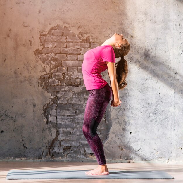 Vista laterale di una giovane donna che fa esercizio di stretching