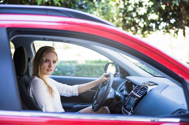 Vista laterale di una giovane donna che si siede all&#39;interno dell&#39;auto