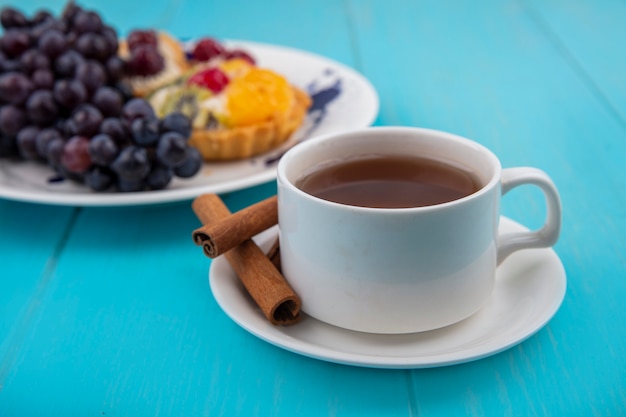 Vista laterale di una tazza di tè con bastoncini di cannella su un fondo di legno blu