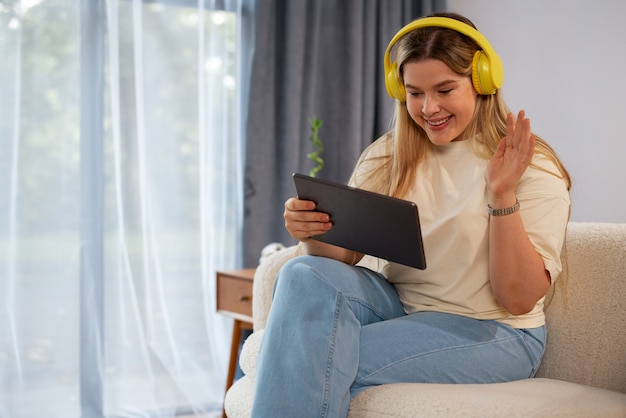 Vista laterale donna che effettua videochiamate con tablet