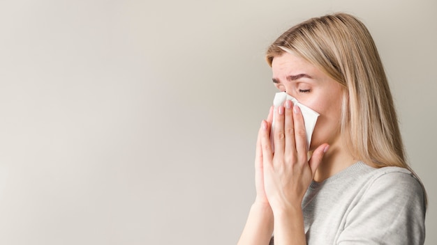 Vista laterale donna che soffia il naso