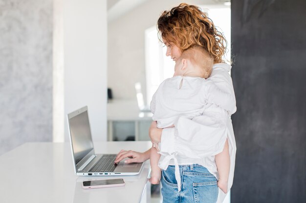 Vista laterale donna con il bambino in braccio