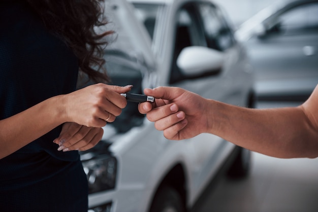 Vista laterale. Donna nel salone dell'auto con il dipendente che riprende la sua auto riparata