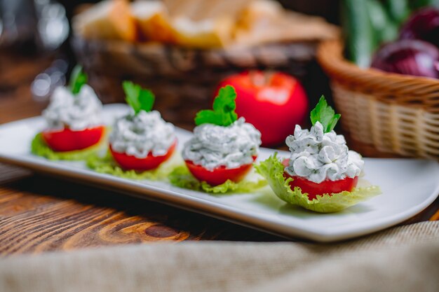 Vista laterale fette di pomodoro ripieni con crema di formaggio ed erbe