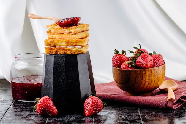 Vista laterale fragola e cialde con crema alla vaniglia e marmellata di fragole in cima