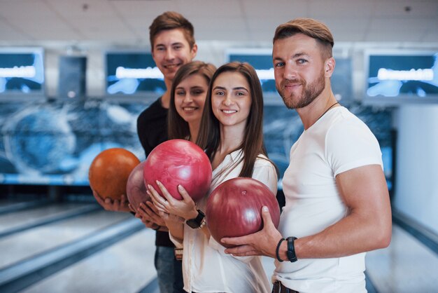 Vista laterale. I giovani amici allegri si divertono al bowling durante i fine settimana