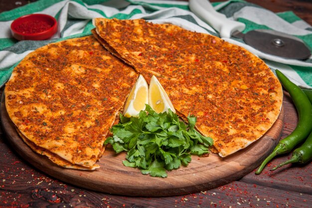 Vista laterale lahmacun con pentole a bordo limone e prezzemolo e peperone verde