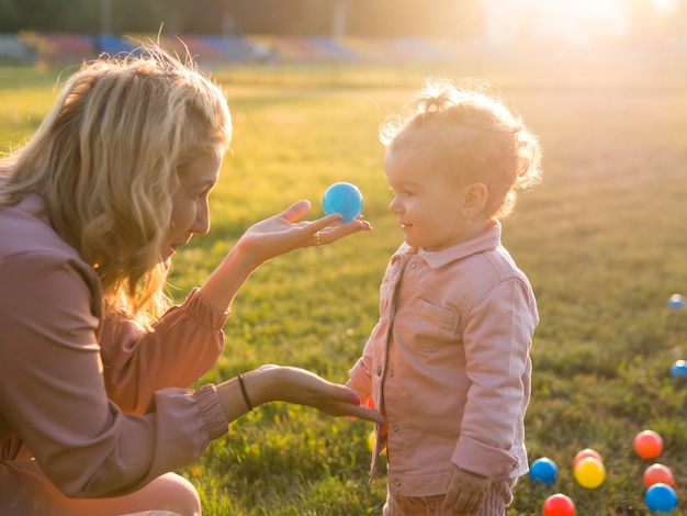 Vista laterale madre e bambino che giocano con le palle di plastica