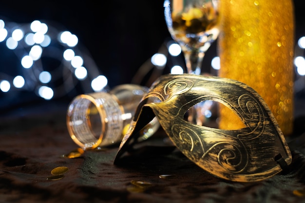Vista laterale parziale di una maschera di carnevale e di un bicchiere con monete