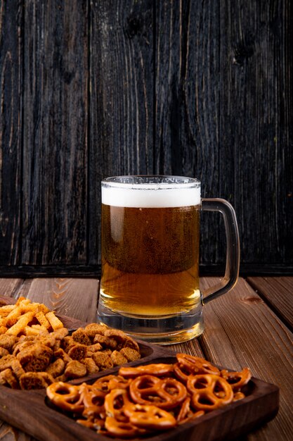 vista laterale Snack per birra con patatine dure e mini brezel con boccale di birra sul tavolo di legno