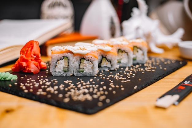 Vista laterale sushi Philadelphia rotoli in salsa con wasabi e zenzero su un supporto