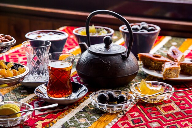 Vista laterale teiera in ghisa con marmellata e una tazza di tè