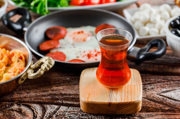 Vista laterale una tazza di tè con deliziosi pasti sulla superficie in legno