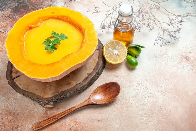 Vista laterale una zuppa di zucca minestra con erbe aromatiche sui rami di albero cucchiaio olio limone