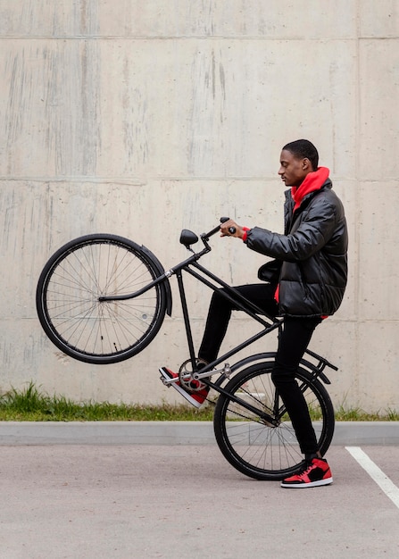 Vista laterale uomo afro-americano e la sua bicicletta