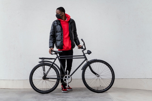 Vista laterale uomo afro-americano e la sua bicicletta