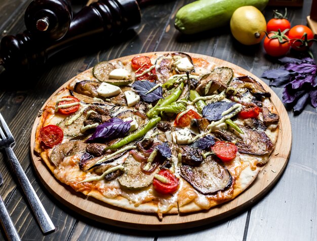 Vista laterale vegetariana del formaggio del pepe del basilico del pomodoro delle olive del fungo della melanzana della pizza