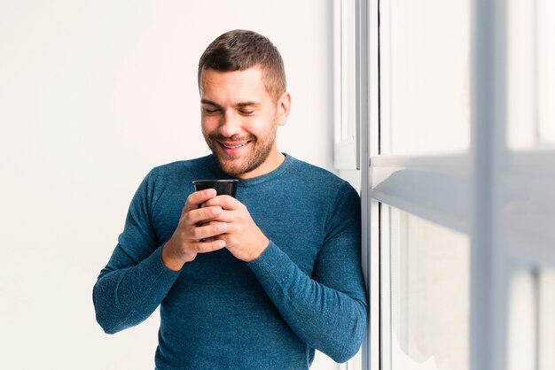 Vista media dell'uomo che tiene una tazza di caffè