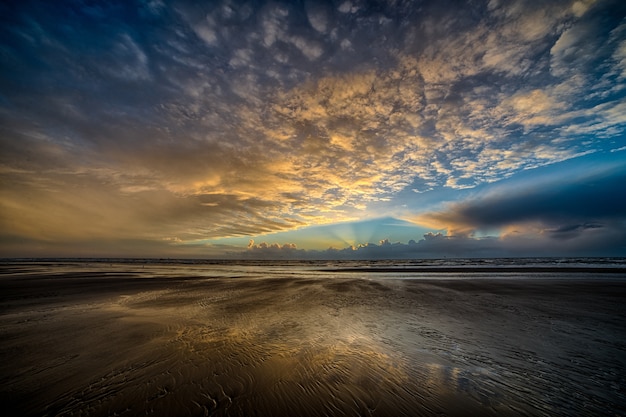 Vista mozzafiato del bellissimo soffitto colorato nuvoloso sopra la riva dell'oceano