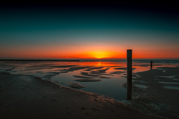 Foto gratuito vista mozzafiato del riflesso del tramonto nell'oceano a domburg, paesi bassi