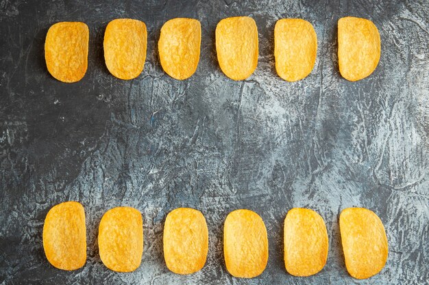 Vista orizzontale del croccante al forno cinque patatine allineate sul tavolo grigio stock photo