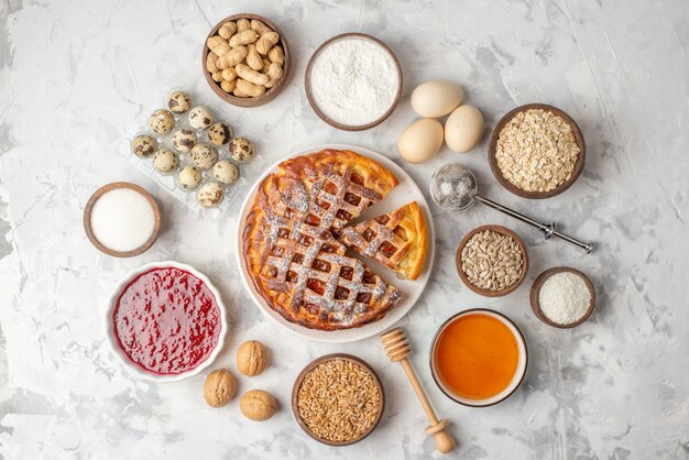 Vista orizzontale della deliziosa torta di marmellata su un piatto bianco nocciole miele uova farina zucchero su tavola di ghiaccio