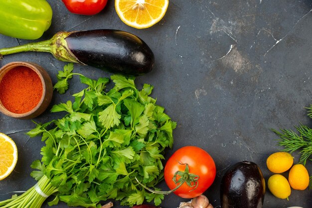 Vista orizzontale dello spazio libero verdure fresche olio caduto bottiglia limoni spezie fasci verdi su tavola nera