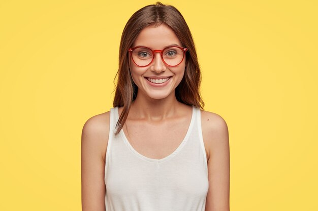 Vista orizzontale di donna bruna emotiva allegra in occhiali ottici e maglia bianca