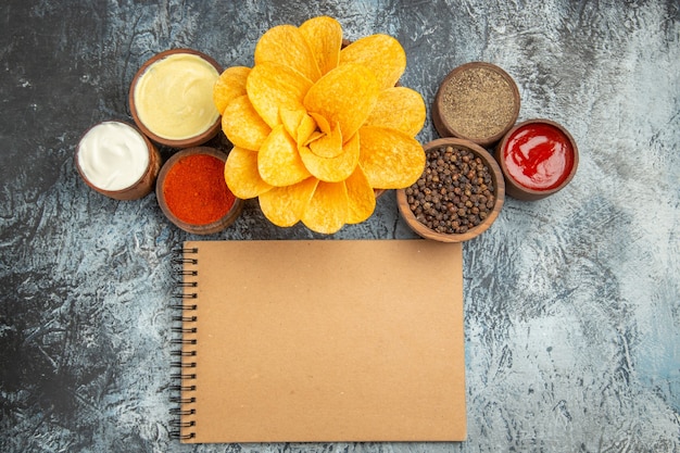 Vista orizzontale di patatine fritte fatte in casa decorate come a forma di fiore e notebook sul tavolo grigio