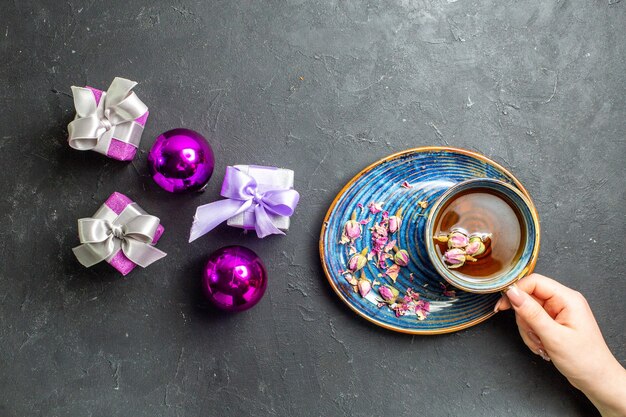 Vista orizzontale di regali colorati e accessori decorativi una tazza di tè nero su sfondo scuro