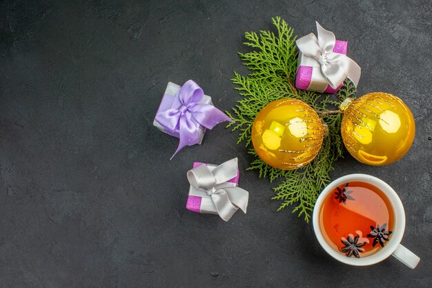 Vista orizzontale di regali colorati una tazza di accessori per la decorazione del tè nero su sfondo scuro