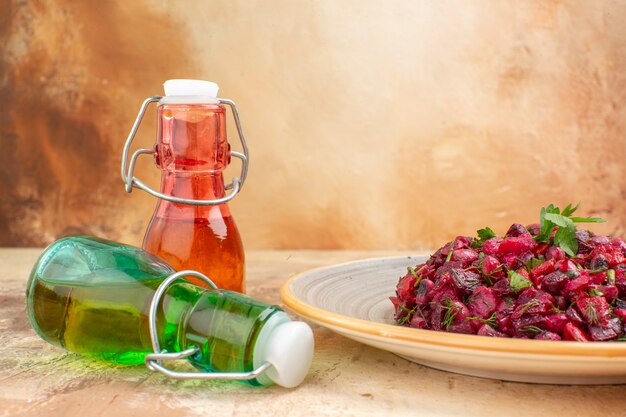 Vista orizzontale di una deliziosa insalata con barbabietola e fagioli e caduta di due bottiglie di olio su sfondo a colori misti