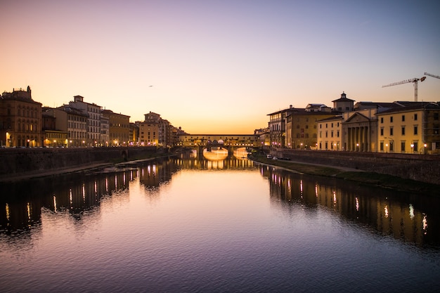 Vista panoramica del famoso Ponte Vecchio con il fiume Arno al tramonto a Firenze, Italia