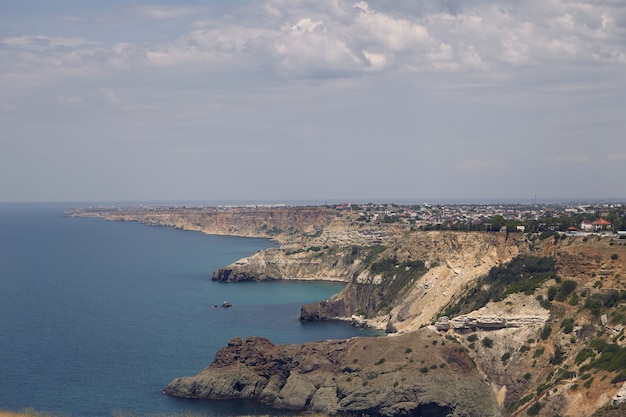 Vista panoramica della costa scoscesa con piccole città dal pacifico mare blu. Seascape e lungo aspro litorale in una giornata estiva nuvolosa. Natura, mare, vacanze, vacanze e concetto di destinazione turistica