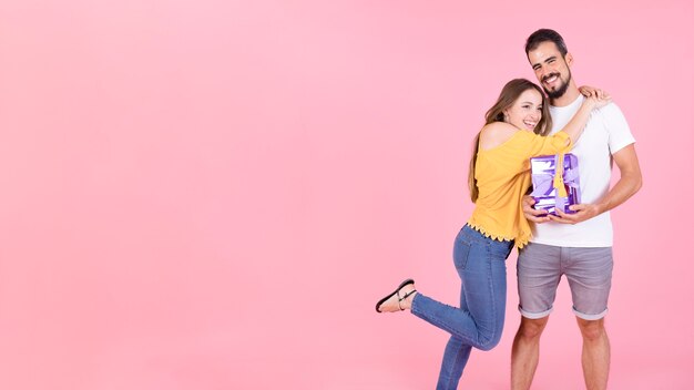 Vista panoramica della donna che abbraccia il suo fidanzato tenendo il contenitore di regalo