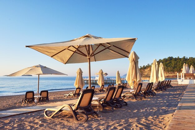 Vista panoramica della spiaggia sabbiosa privata con lettini e ombrelloni sul mare e sulle montagne. Ricorrere.