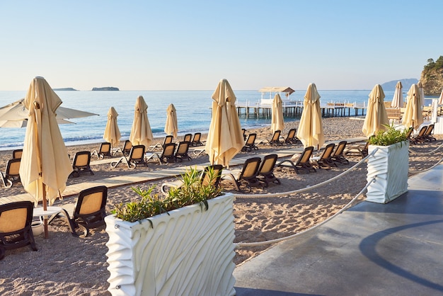 Vista panoramica della spiaggia sabbiosa privata con lettini e ombrelloni sul mare e sulle montagne. Ricorrere.