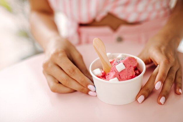 Vista parziale della donna che mangia il gelato. Messa a fuoco selettiva della donna con dessert dolce.