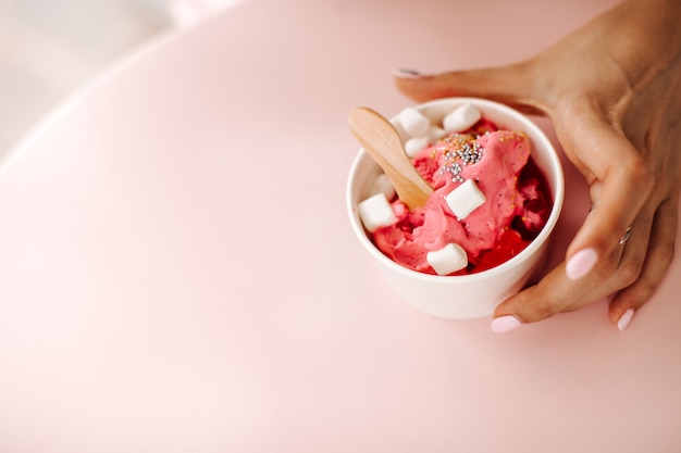 Vista parziale della donna che tiene la tazza con il gelato. Donna che gode del dolce dessert con marshmallow.