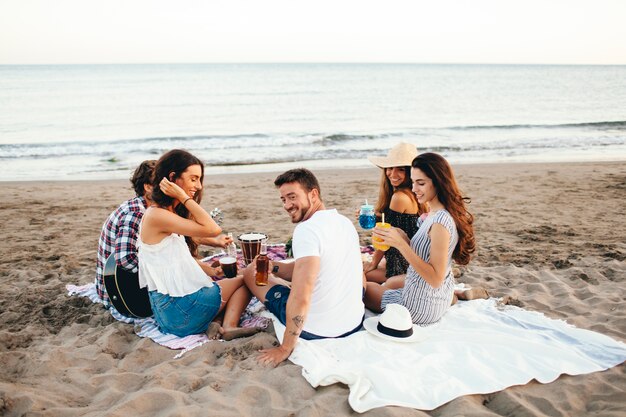 Vista posteriore degli amici che hanno una festa sulla spiaggia