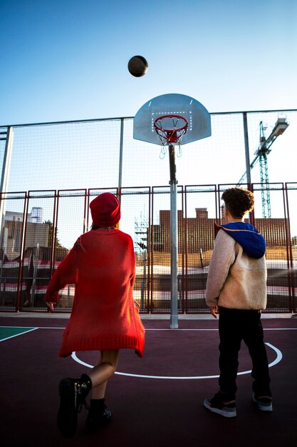 Vista posteriore dei bambini che giocano a basket insieme all'aperto